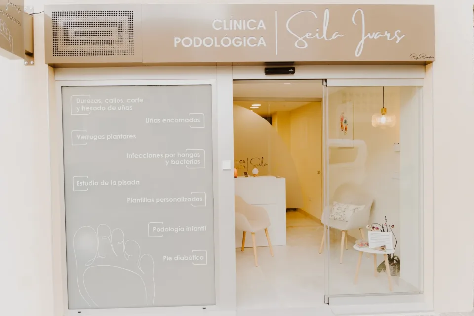 Frontage of Clínica Podológica Seila Ivars, with the sign and the treatments lettered on the glass